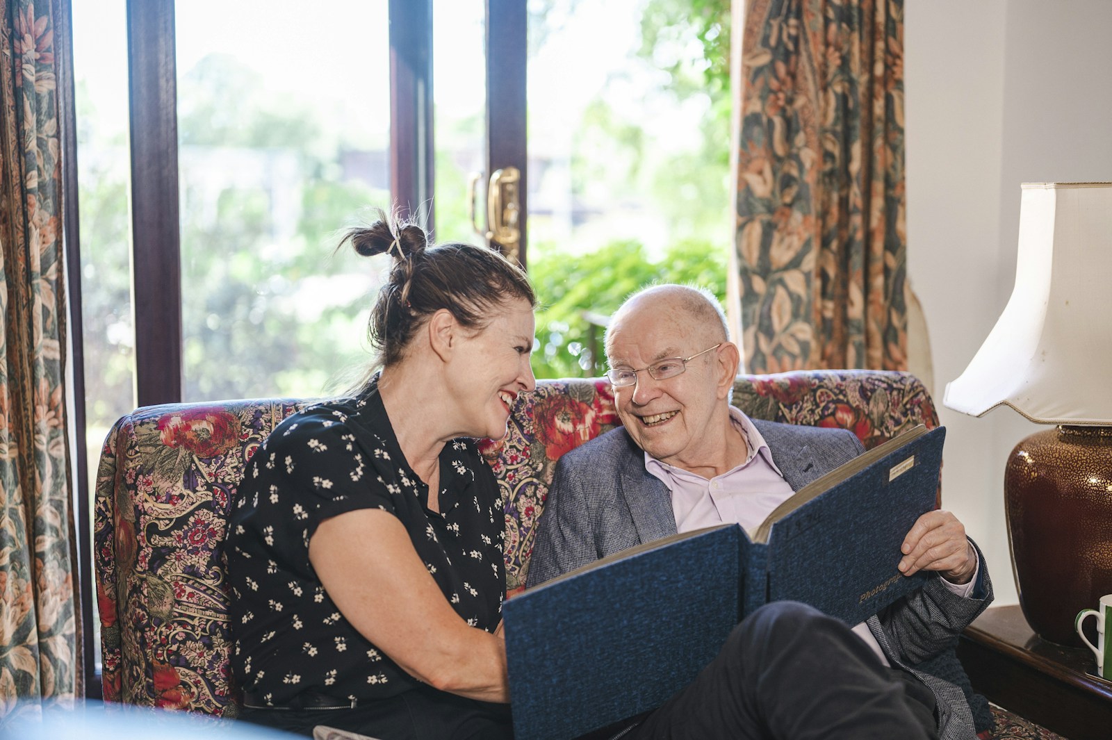 A caregiver and an older man laughing as they go through his care folder