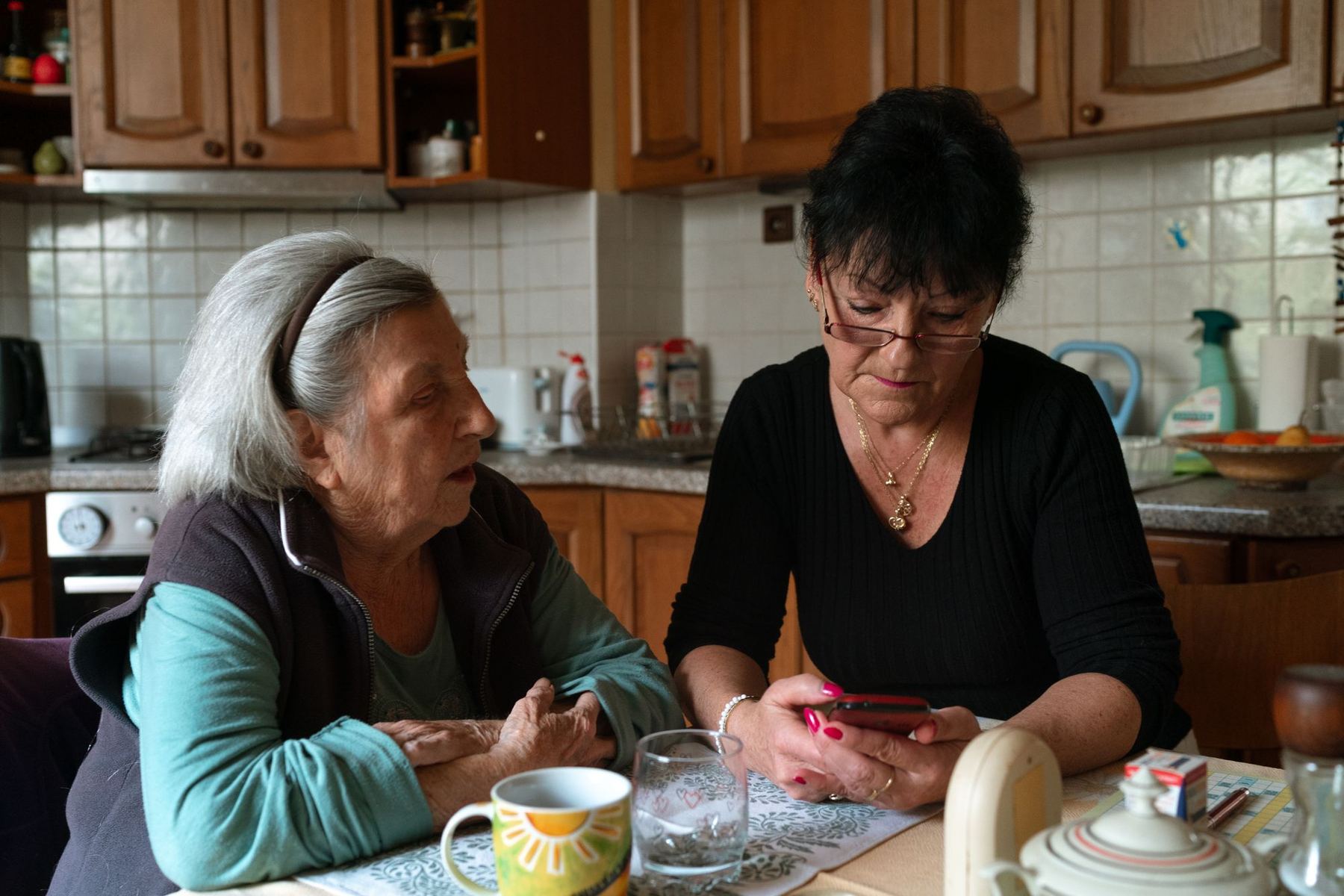 A caregiver and an older woman arranging the week’s visits at her kitchen table