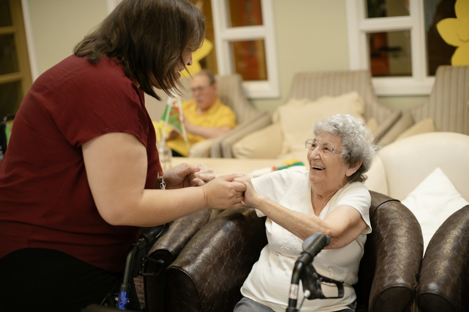 A caregiver walking beside an older woman using a walker at home